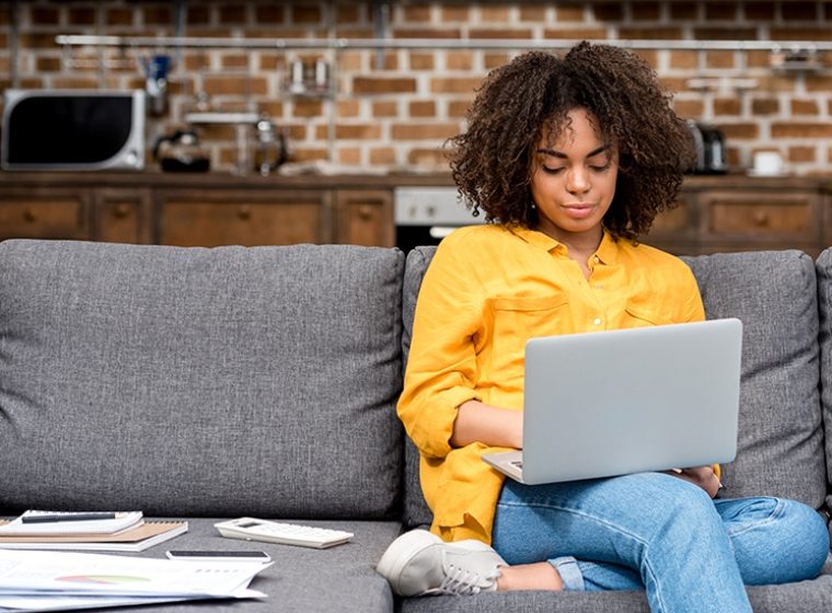 woman sits on couch while remote working